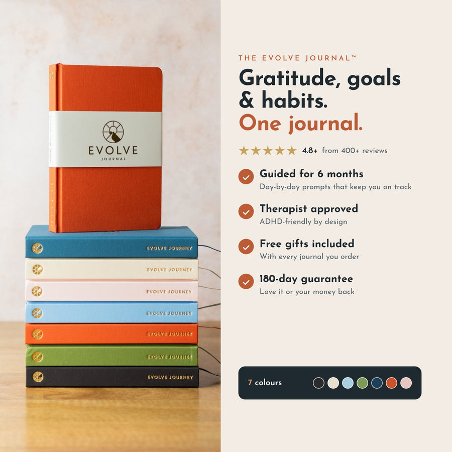The Evolve Journal guided journal in terra cotta on a stack of all seven colours: gratitude, goals and habits in one journal, guided for 6 months, free gifts included